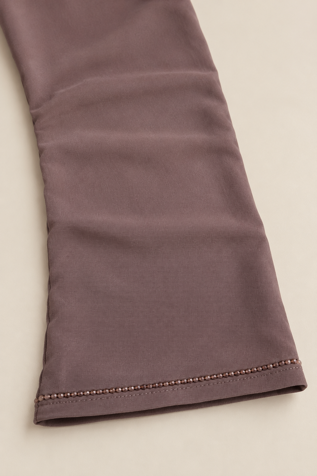 Détail de la manche taupe : fine bordure de perles facettées et ourlet cousu.
