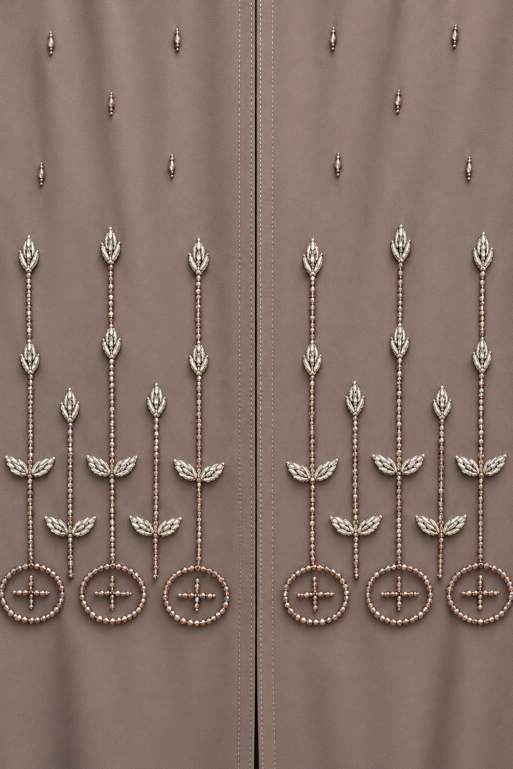 Gros plan sur les bourgeons et feuilles argentés, les tiges et les cercles perlés de l’abaya taupe.