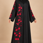 Abaya noire à broderies rouges portée par une mannequin métisse arabe, voile couvrant la poitrine
