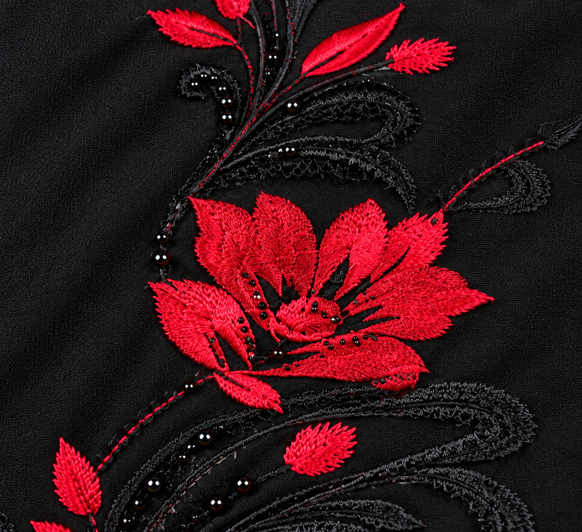 Gros plan de la broderie florale rouge et des feuillages noirs