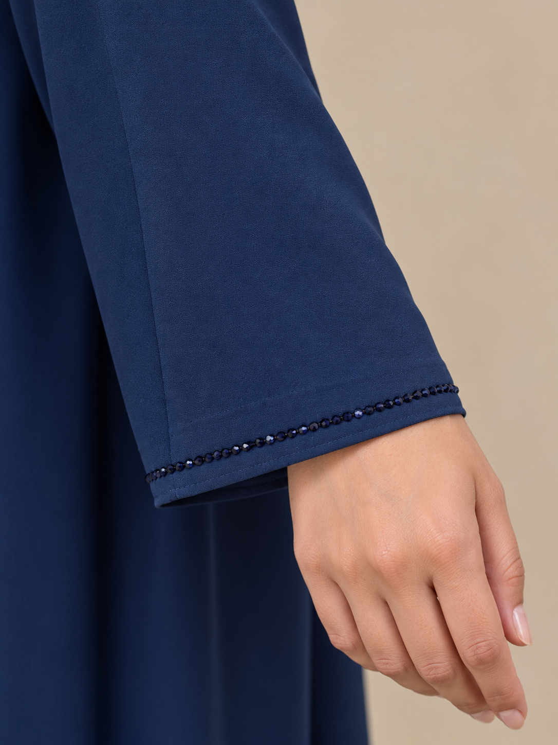 Détail de la manche bleue et de sa bordure de perles