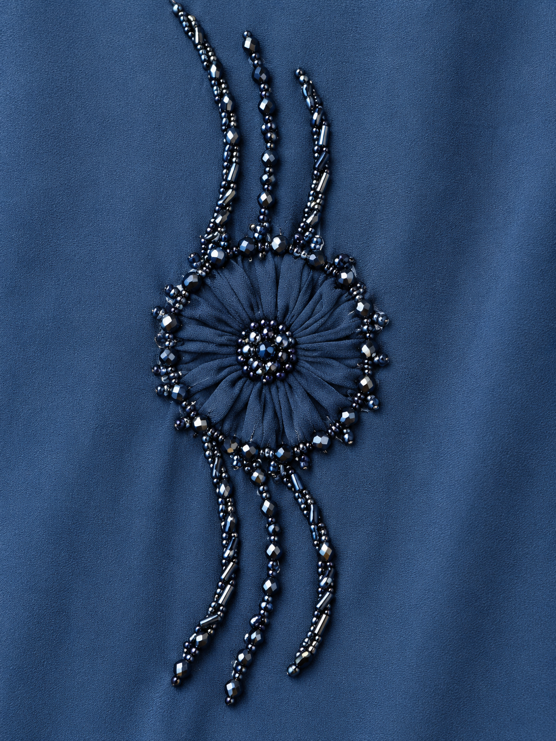 Détail du motif circulaire et des ornements perlés de l’abaya bleue