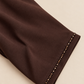 Gros plan sur la bordure perlée et la couture du poignet de l’abaya chocolat