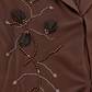 Détail des rameaux perlés et des pétales sombres en relief de l’abaya chocolat