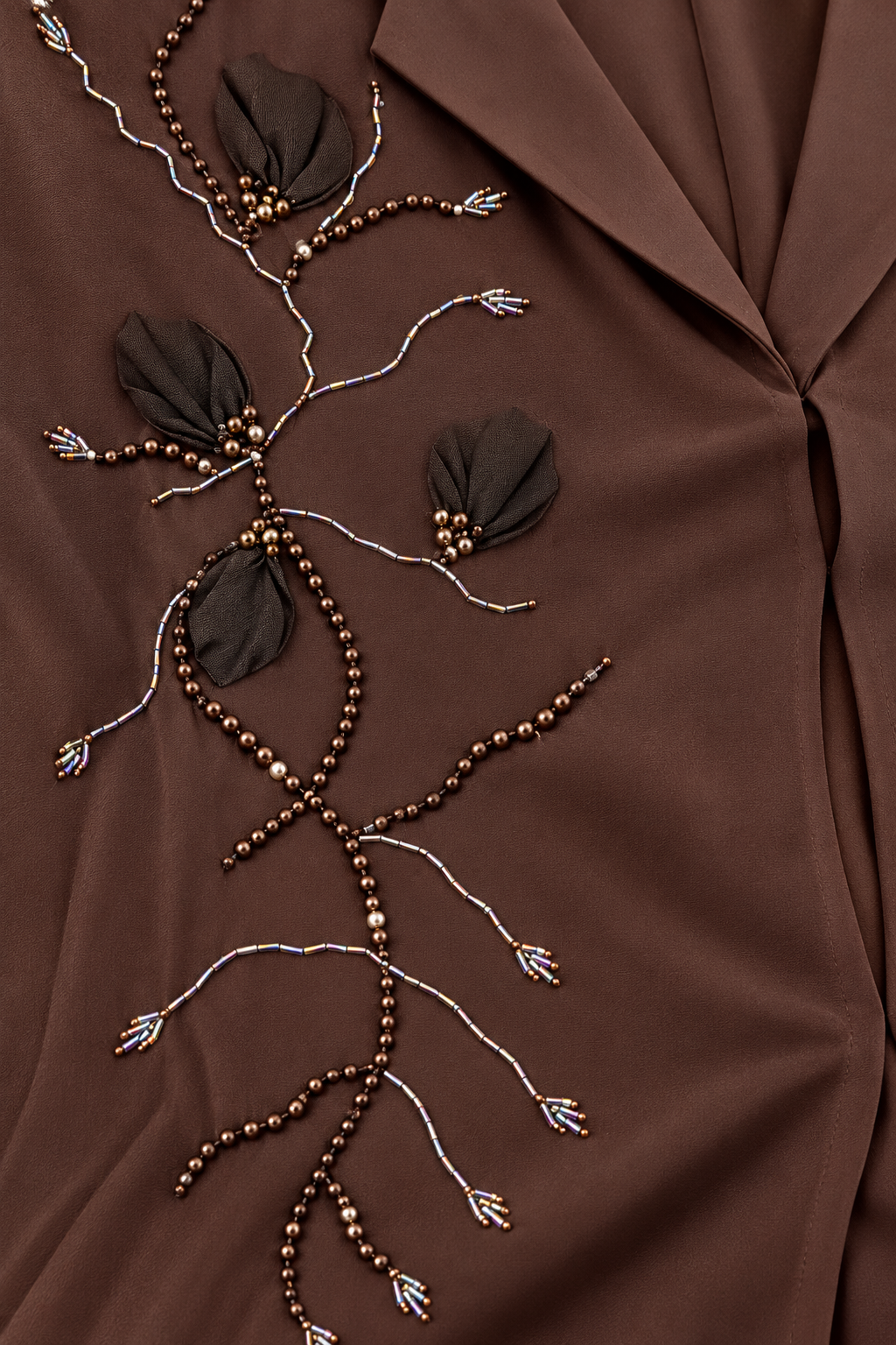 Détail des rameaux perlés et des pétales sombres en relief de l’abaya chocolat