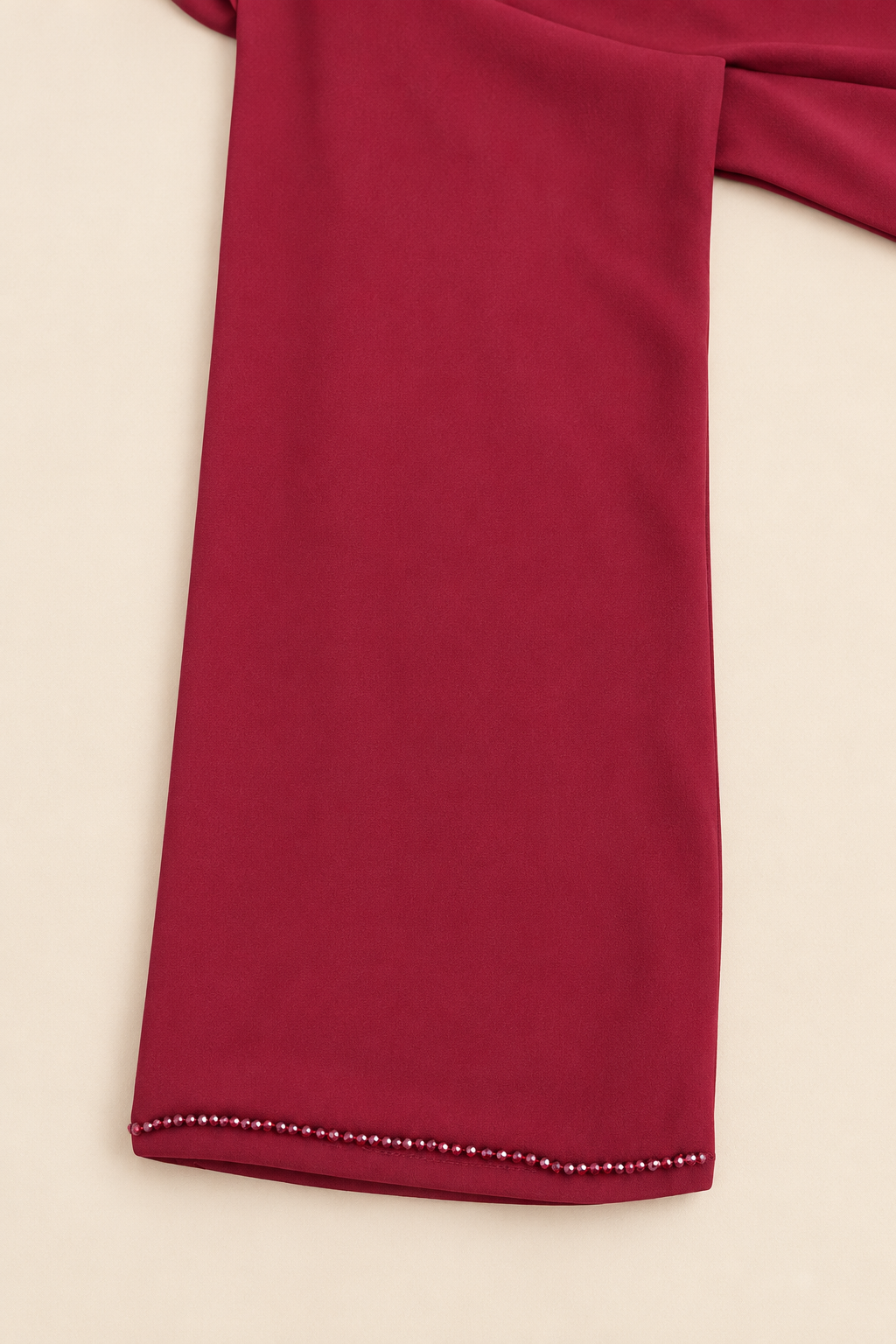 Détail de la manche bordeaux, bordure perlée et finition du poignet