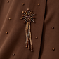 Détail du motif floral perlé chocolat et de ses fines franges