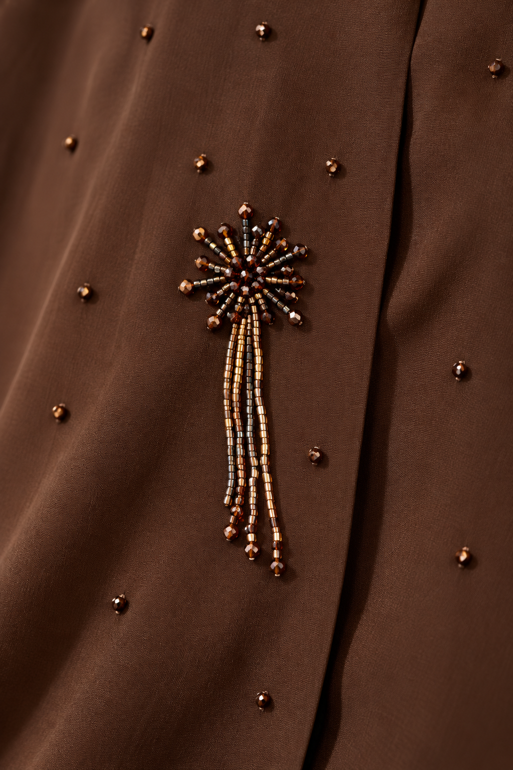 Détail du motif floral perlé chocolat et de ses fines franges