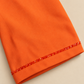 Détail du poignet orange, bordure perlée et finition cousue