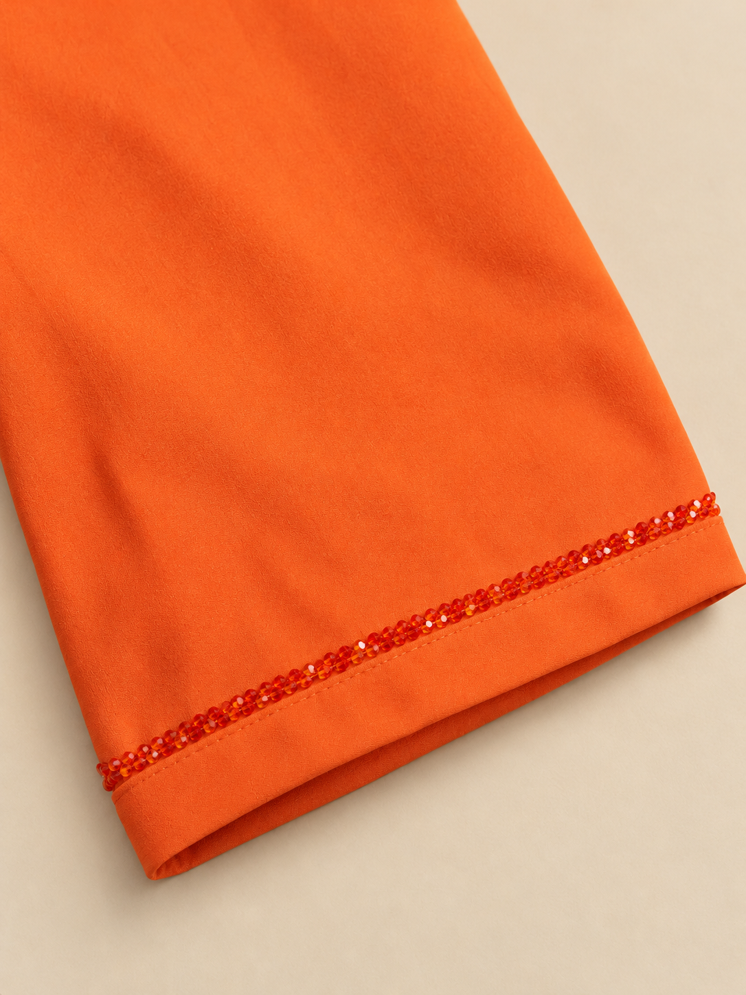 Détail du poignet orange, bordure perlée et finition cousue