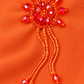 Détail du motif perlé orange et de ses fines franges