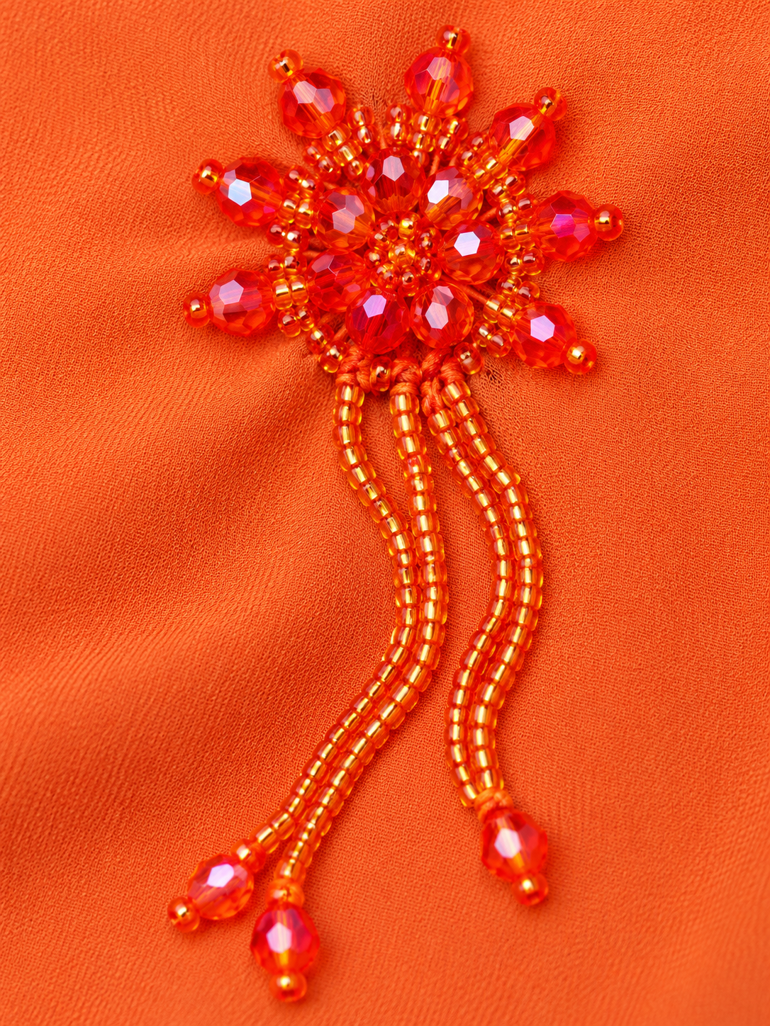Détail du motif perlé orange et de ses fines franges