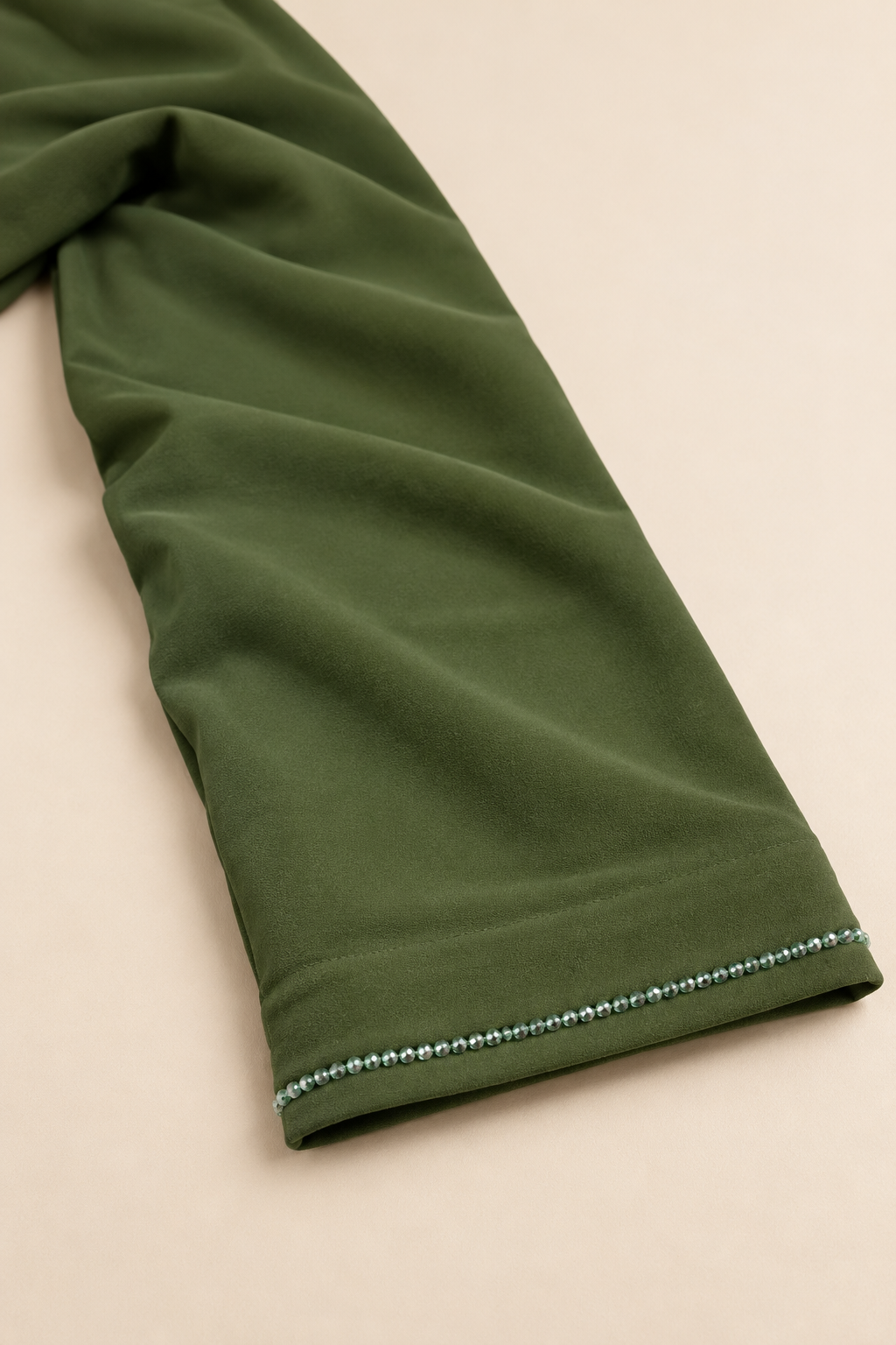Détail du poignet de l’abaya Volutes vert olive, bordure perlée et finition de l’ourlet